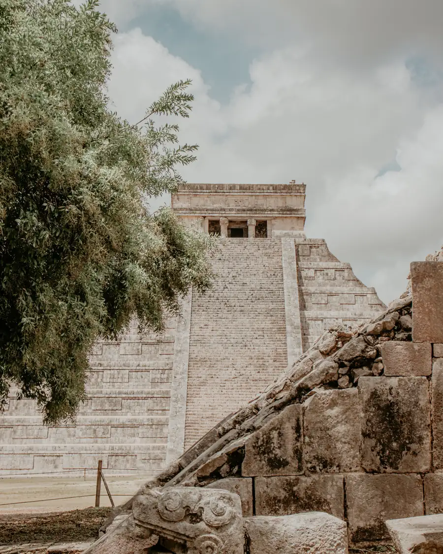 The Temple of Kukulcán at Chichén Itzá, framed by a tree and a carved serpent head
